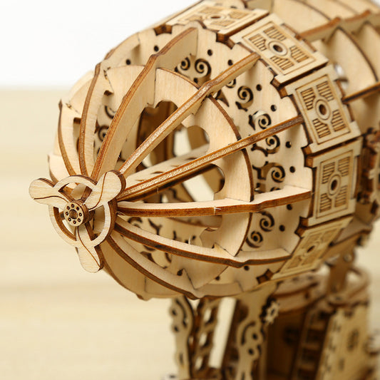 Wooden model of a steampunk-style airship on a wooden surface with a white background