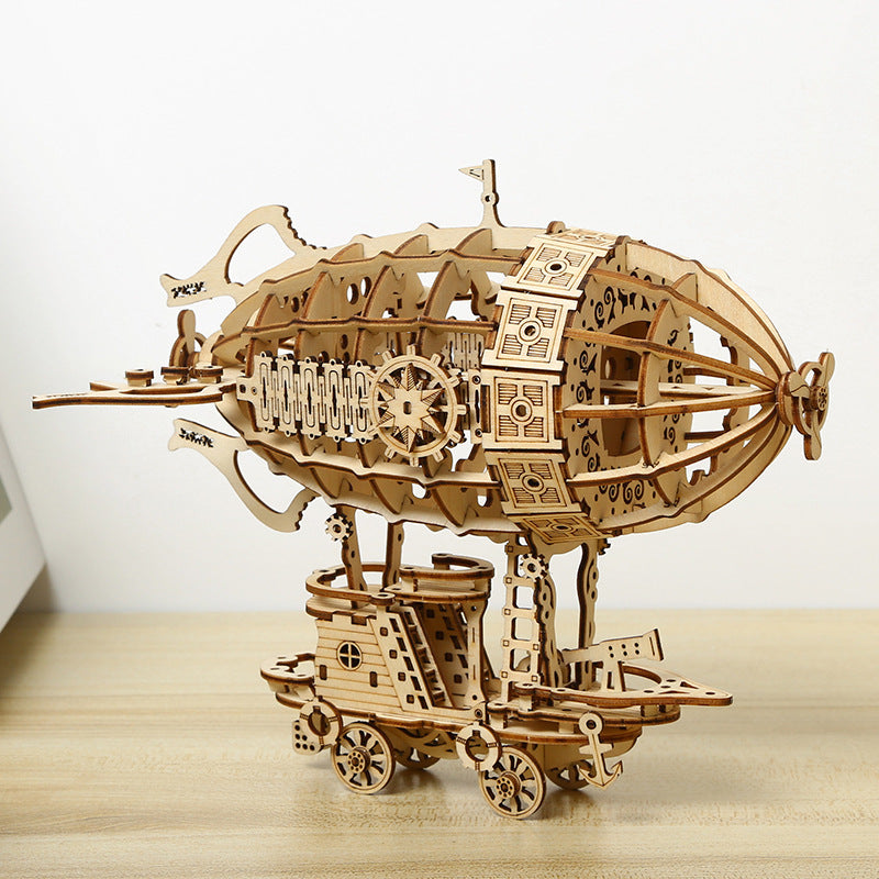 Wooden model of a steampunk-style airship on a wooden surface with a white background