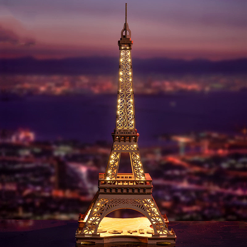 Model of the Eiffel Tower at night with a blurred cityscape in the background