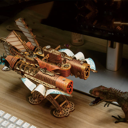 Wooden steampunk-style model ship on a desk with a lizard figurine.
