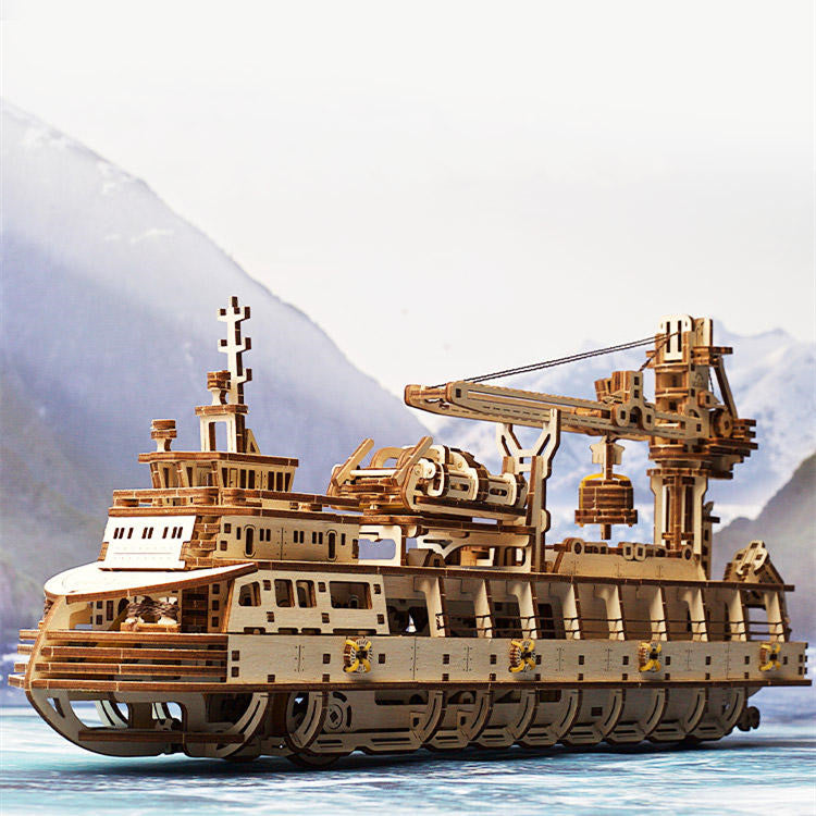 Wooden model ship with detailed structure against a mountainous background