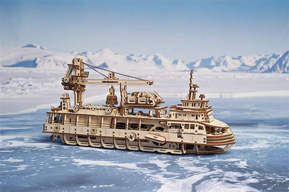 Wooden model of a ship in icy waters with mountains in the background