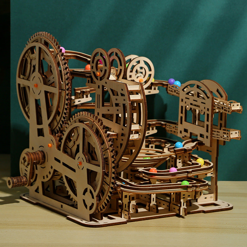 Wooden mechanical model with gears and balls on a wooden surface against a teal background